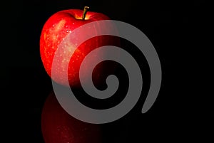 A red apple with water drops on skin on black background with copy space. Healthy fruit and healthy food concept. Vegan
