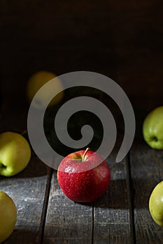 Red apple in water drops on wooden background texture