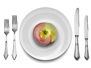 Red apple on white plate with knife and fork,