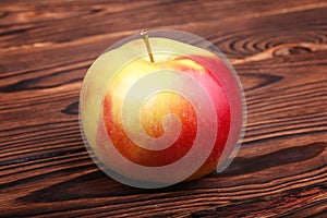 A red apple on a wooden background. A colorful and sweet apple. A healthful and nutritious snack. A single organic ingredient.