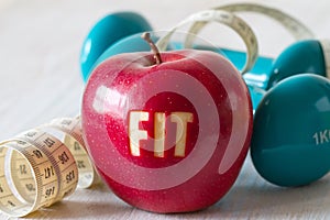 Red apple with word FIT, dumbbells and measuring tape, healthy diet and sport concept