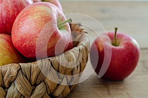 Red apples are in the basket on wooden table