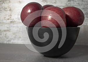 Red apples in a black plate on a gray wooden background. Vitamin-rich apples on the table at home for the whole family. Autumn bac
