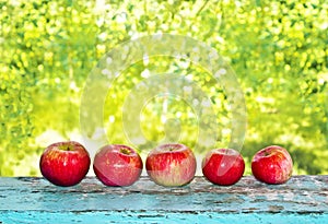Red apples on a blue old wooden table.