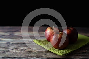 Red apples on the green cloth on the wooden table picture.