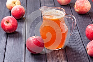 Red apples and juice in the pitcher on table