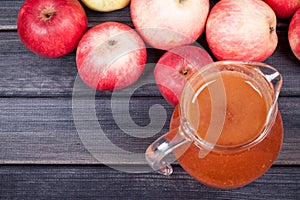 Red apples and juice in the pitcher on wooden table