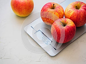 Red apples on kitchen scales on white background. Product weighing