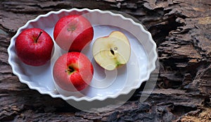 Red apples in a plate on a wooden background