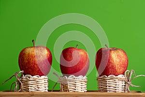 Red apples in three small baskets and green background