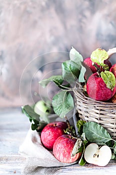 Red apples in a wicker basket on a wooden table, blurred background