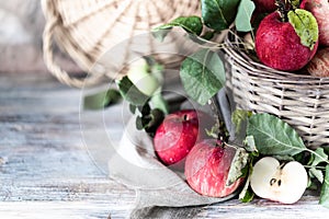 Red apples in a wicker basket on a wooden table, blurred background
