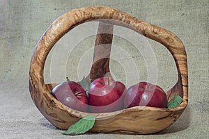 Red apples in wooden basket on natural sacking material