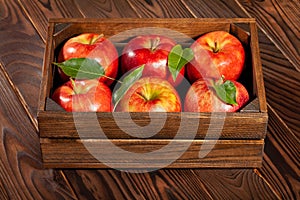 Red apples in wooden box on brown wood