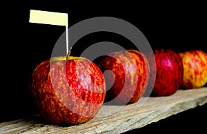 Red apples and yollow label put on wooden with black background