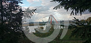 Red arch of the cable-stayed suspension bridge over the wide Ob River. Novosibirsk, Russia.