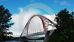 Red arch of the cable-stayed suspension bridge over the wide Ob River. Novosibirsk, Russia.