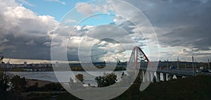 Red arch of the cable-stayed suspension bridge over the wide Ob River. Novosibirsk, Russia.