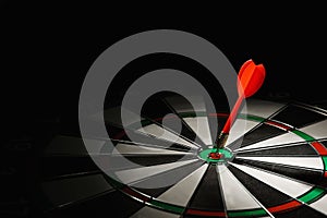 Red arrow hitting target on dart board against black background