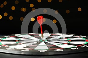 Red arrow hitting target on dart board against blurred