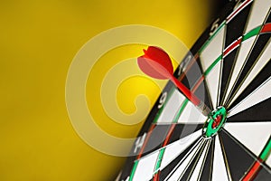 Red arrow hitting target on dart against yellow background. Space for text