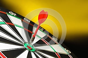 Red arrow hitting target on dart board  yellow background. Space for text