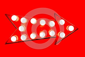 Red arrow shaped vintage colorful illuminated metallic display direction sign with glowing light bulbs isolated