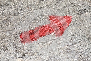 Red arrow on a stone close-up, direction forward upward ascending