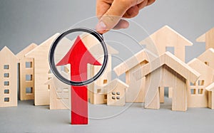 Red arrow up and miniature wooden houses. The concept of rising property prices. High mortgage rates. Expensive rental apartment.