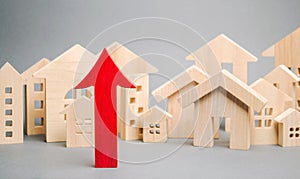 Red arrow up and miniature wooden houses. The concept of rising property prices. High mortgage rates. Expensive rental apartment.