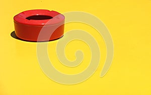 Red ashtray on a yellow surface