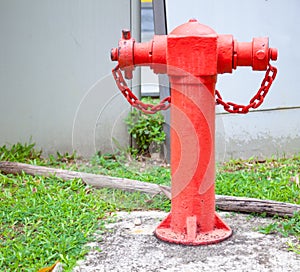 Red Asian Vintage above-ground pillar-type Fire Hydrant at a street corner with building background. Fire Extinguishing, Safety