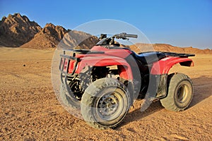 Red ATV in a desert with mountains view