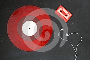 Red Audio cassette and Red vinyl record on a black background. Retro style. Top view. With White headphones .