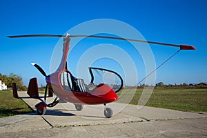 Red autogyro parked at the airfield in sunny day