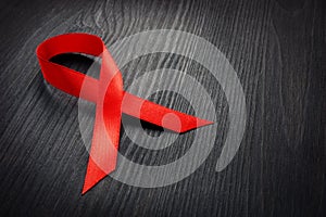 Red awareness ribbon on a dark desk. HIV AIDS