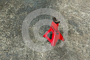 Red axle stand on floor. Red high lift jack stand on the floor. Red extendable jack stands are used to lift up and support.