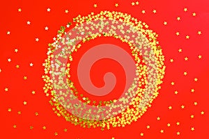 Red backdrop with glitter and golden stars confetti in circle. Festive holiday bright background