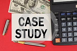 On a red background, among the money, a calculator and a pen lies a sign with the text - CASE STUDY