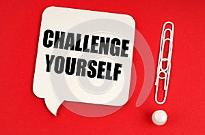 On a red background, paper clips are an exclamation mark and a thought plate with the inscription - CHALLENGE YOURSELF