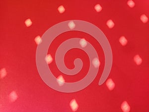 Red background with polka dots. Rays of the sun shining through the holes in the blinds and painting light blurry circles on the