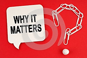 On a red background are a question mark made of paper clips and a sign with the inscription - WHY IT MATTERS