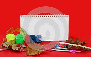 Red background with school stationery, back to school concept, empty notebook