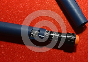 On a red background, a syringe pen for the introduction of insulin to a patient with diabetes, endocrinological diseases