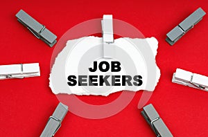 On a red background, there are clothespins and a piece of paper with the inscription - Job Seekers