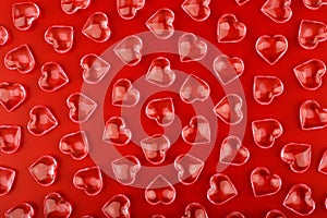 Red background with transparent glossy glass hearts. Concept of love and St. Valentine's day