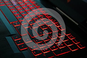 Red backlight on a modern keyboard of gaming laptop in the dark