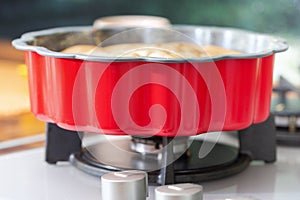A red baking pan stands on a gas kitchen stove.