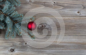 Red Ball Christmas Ornament on Pine Tree Branch with Rustic Wood