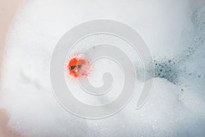 Red ball floating in a bubble bath.